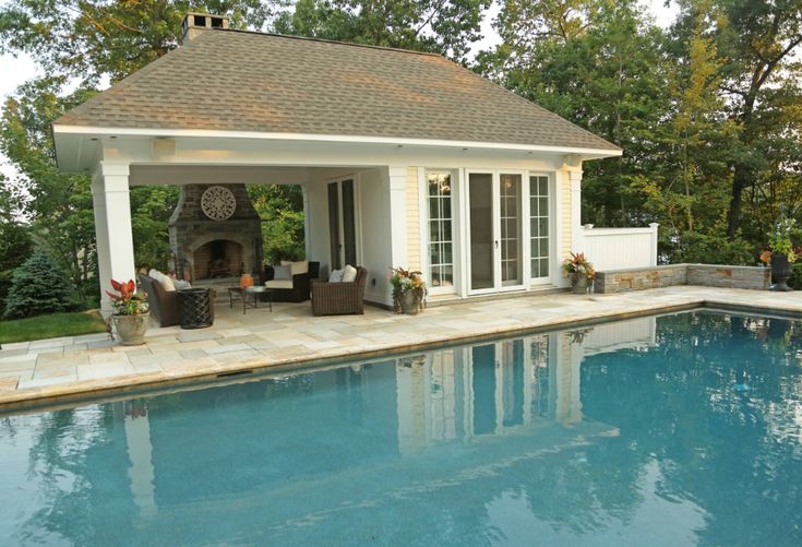 a pool house with an outdoor fireplace next to it