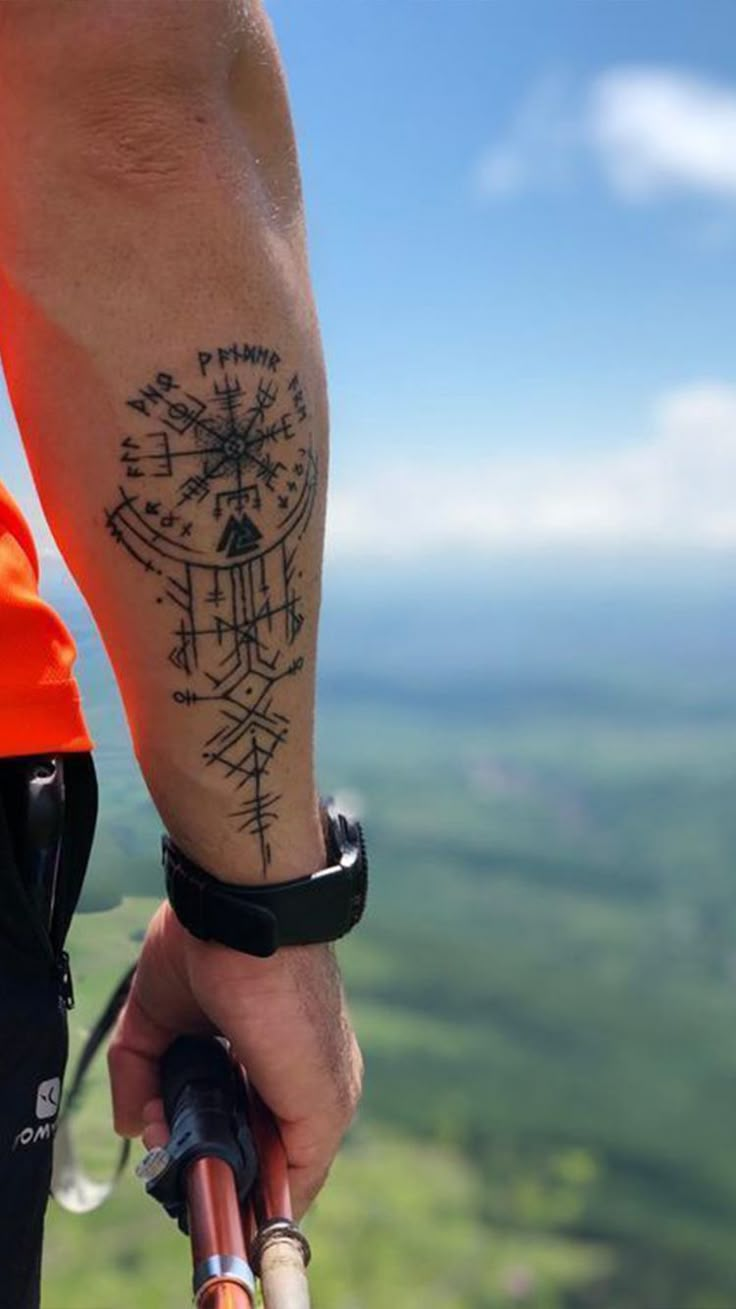 a man with a compass tattoo on his arm