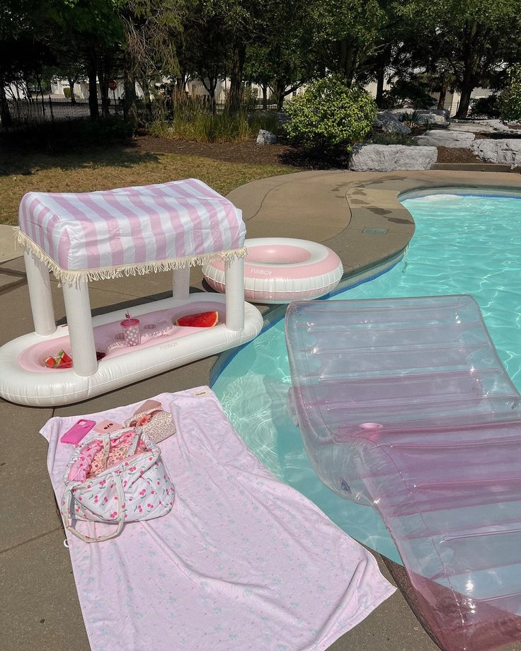 an inflatable pool with pink and white sheets on the ground next to it