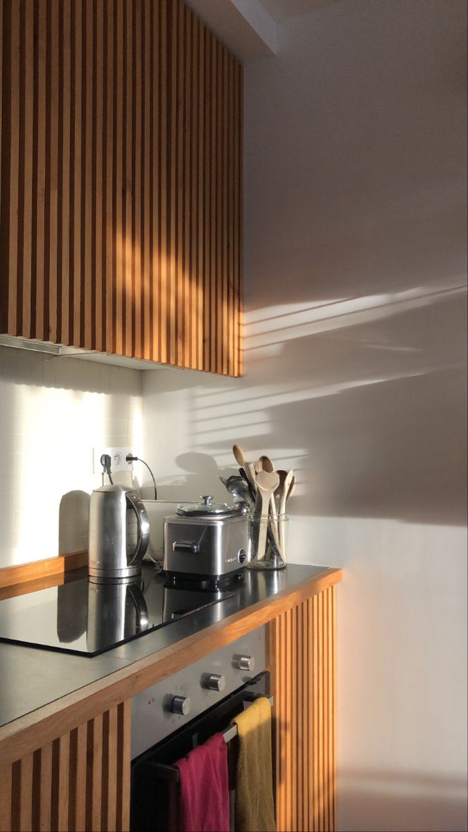 a stove top oven sitting inside of a kitchen next to a wooden cabinet with utensils on it