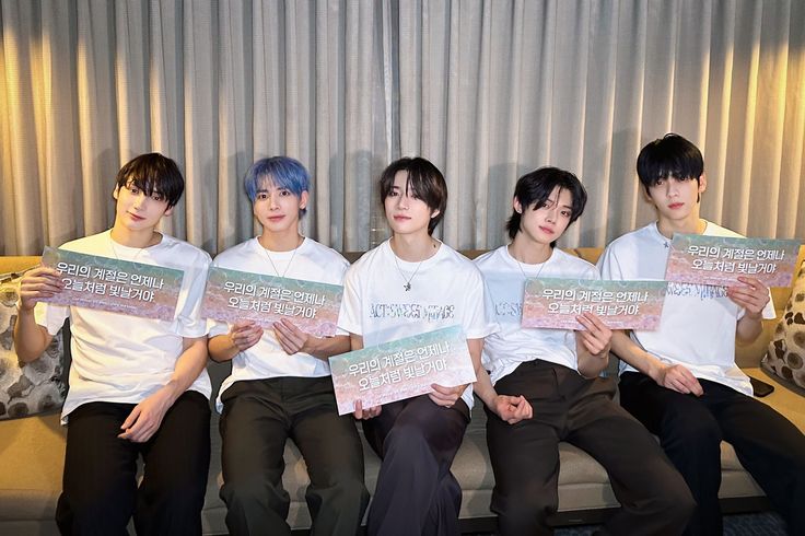 four young men sitting on a couch holding up papers with words written on them in different languages