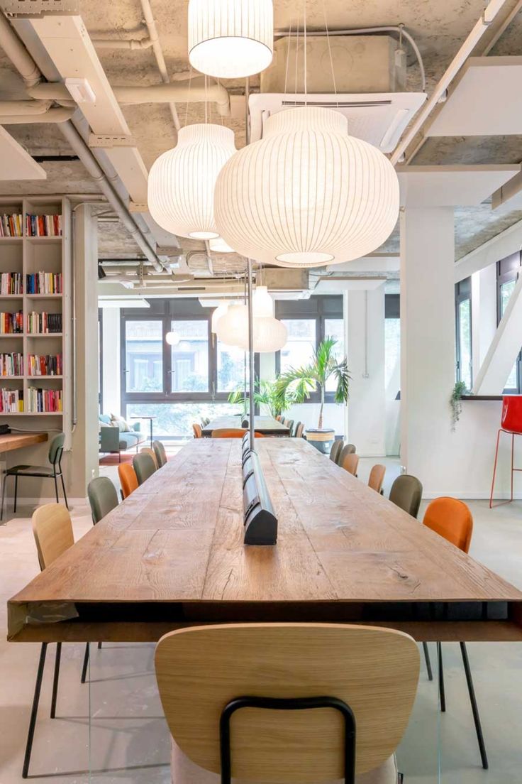 a large wooden table surrounded by chairs and bookshelves