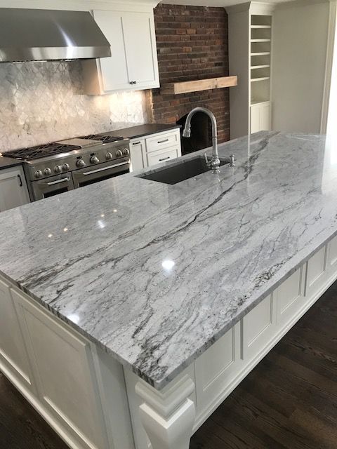 a large kitchen with an island in the middle and white cabinets on both sides, along with stainless steel appliances