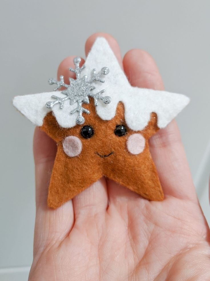 a hand holding a brown and white felt star ornament