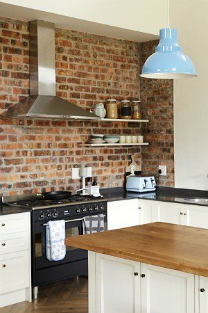 a kitchen with brick walls and white cabinets