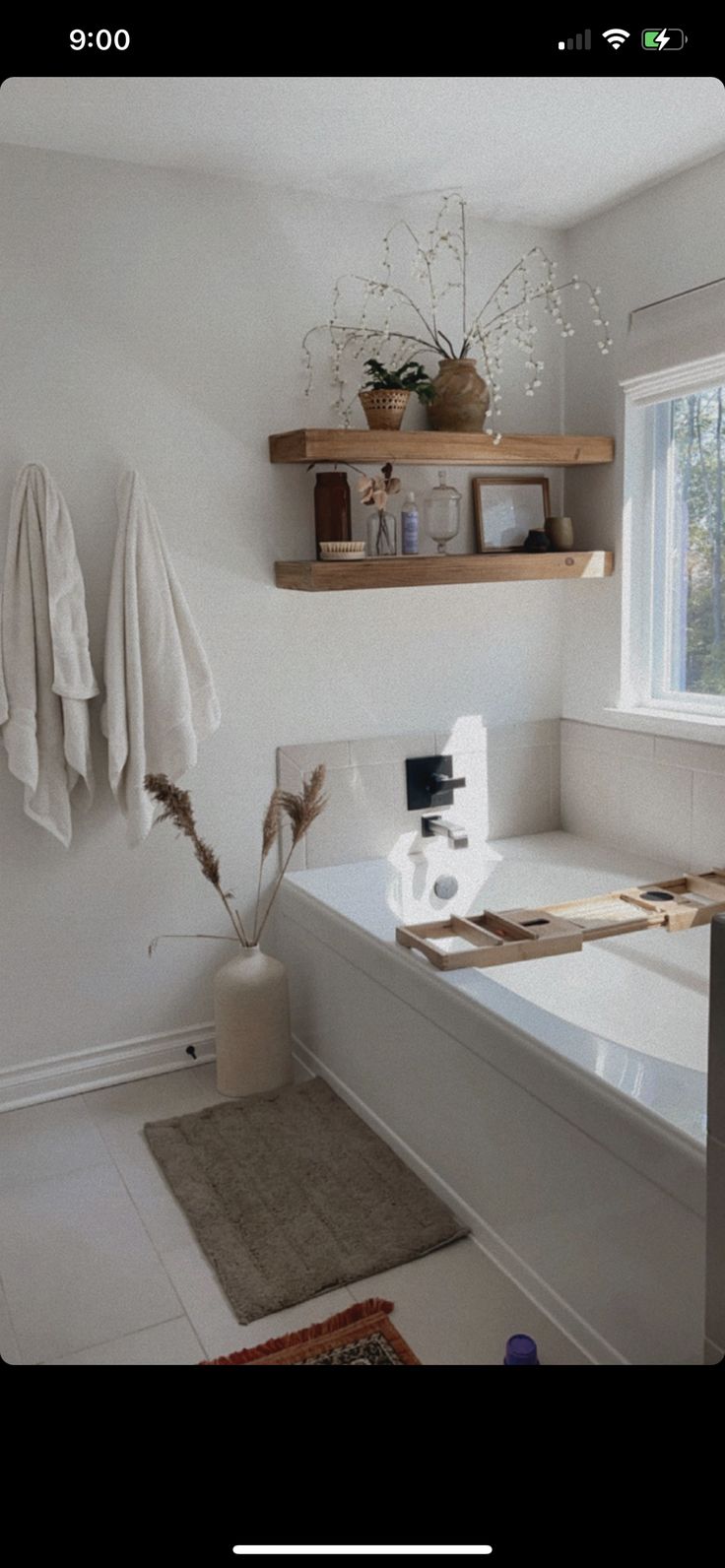 a bath room with a tub a shelf and some towels on the wall next to it