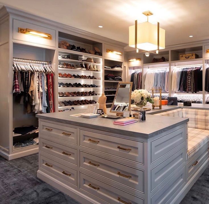 a walk in closet filled with lots of drawers and clothes hanging on the wall next to a counter