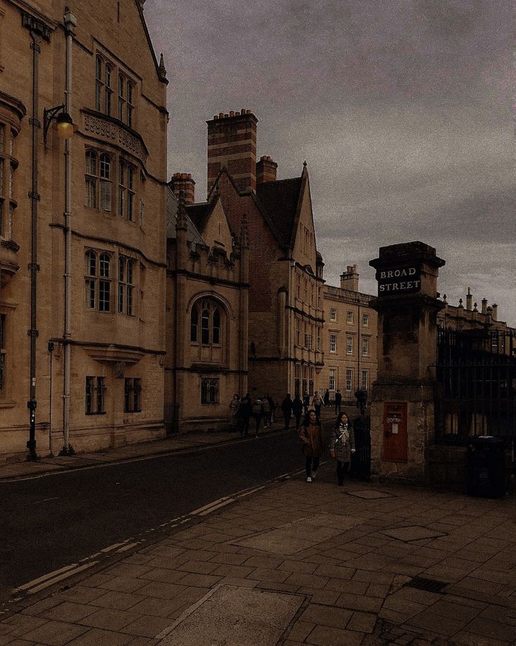 people are walking down the street in front of old buildings on a gloomy day