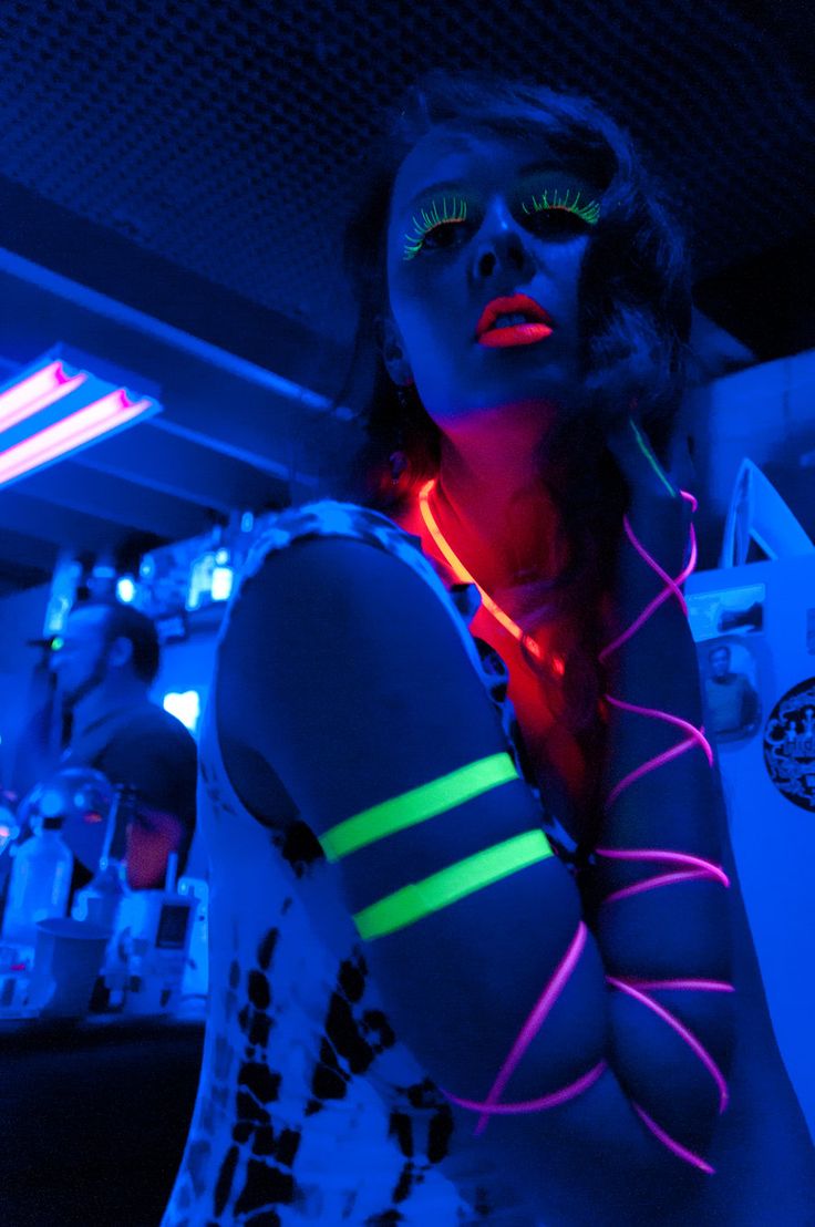 a woman with neon lights on her arm and chest in a room full of people