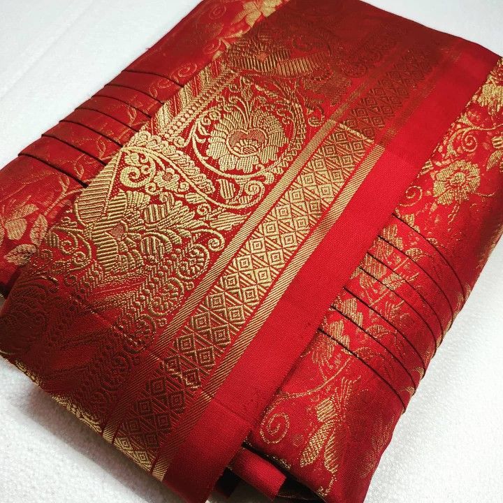 a red and gold brocaded cloth on a white surface