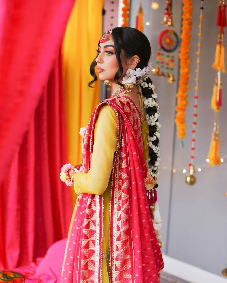 a woman in a red and yellow outfit standing next to a wall with decorations on it