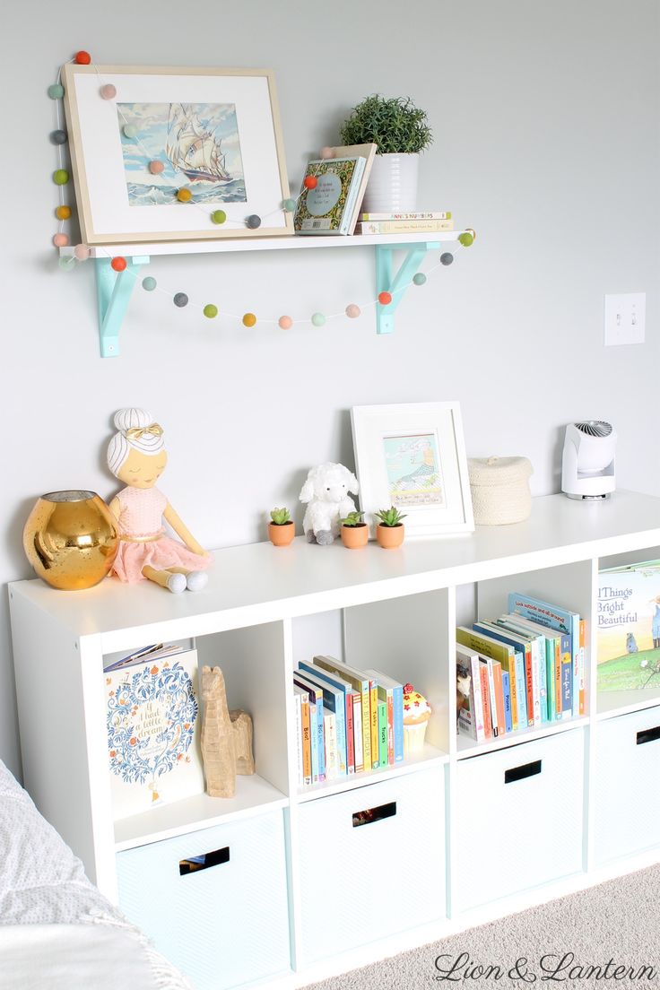 a white book shelf with books and toys on it in a child's room