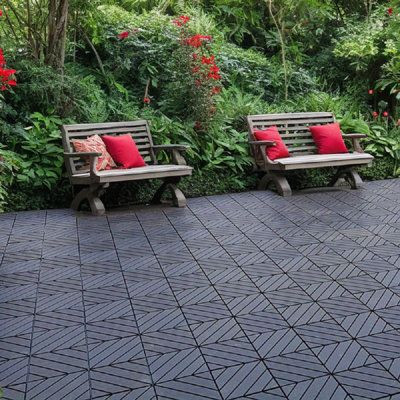 two wooden benches sitting next to each other on a brick walkway surrounded by greenery