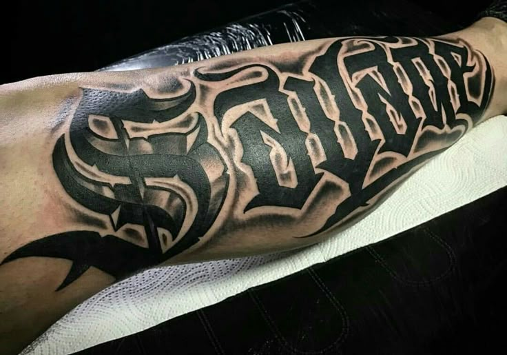 a man's arm with an old school style lettering tattoo on the left leg