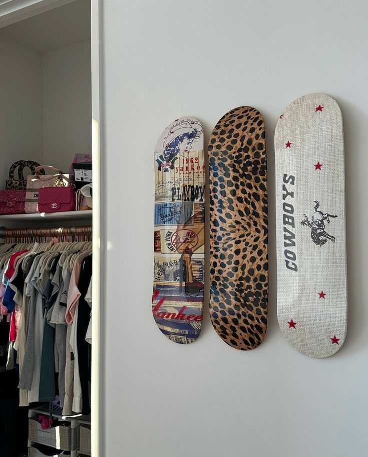 two skateboards are hanging on the wall next to each other in a closet with clothes