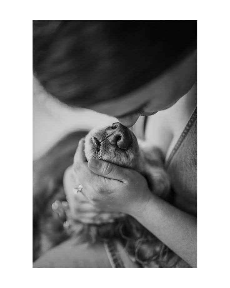 black and white photograph of a woman holding a small dog's face in her hands