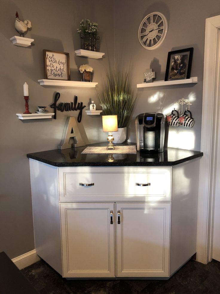 a kitchen area with white cabinets and black counter top, clock on the wall above it