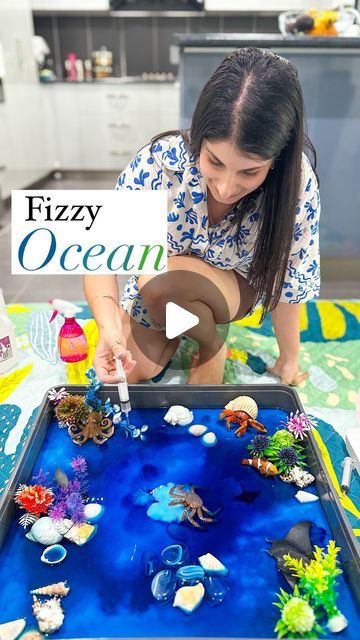 a girl is playing with an ocean scene made out of plastic bottles and water beads