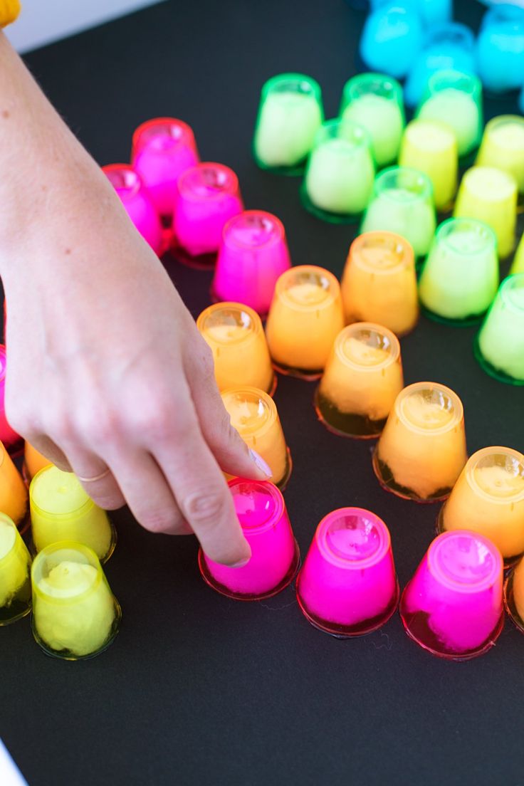 a person's hand reaching for an item in front of many colored cups