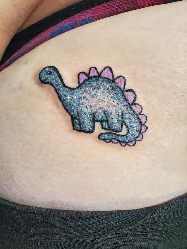 a small dinosaur tattoo on the stomach