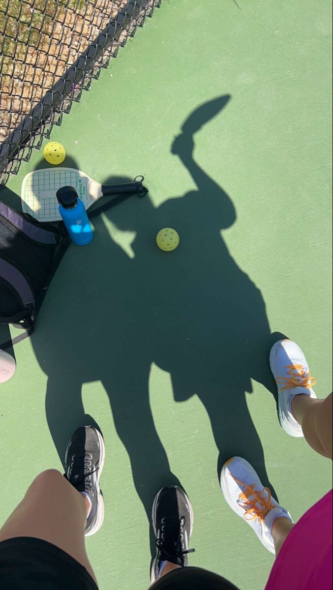 two people standing on a tennis court with rackets and balls