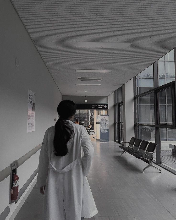 a woman is walking down the hallway in an office building with chairs on either side