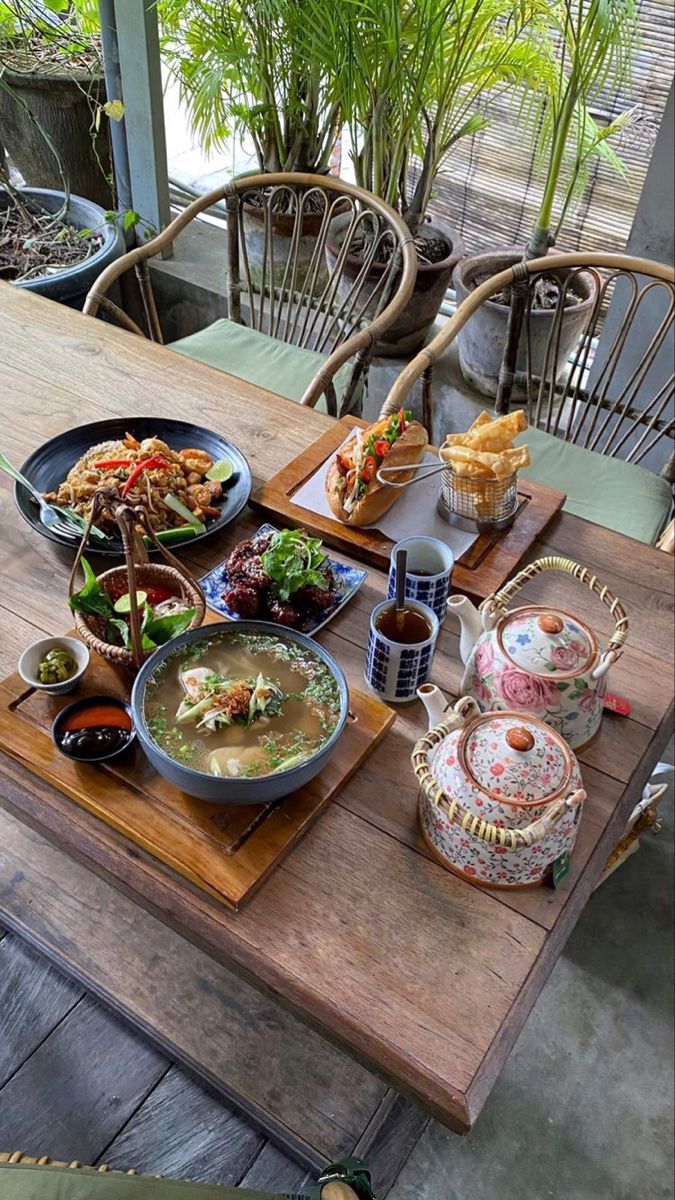 a wooden table topped with plates and bowls filled with different types of food on top of it