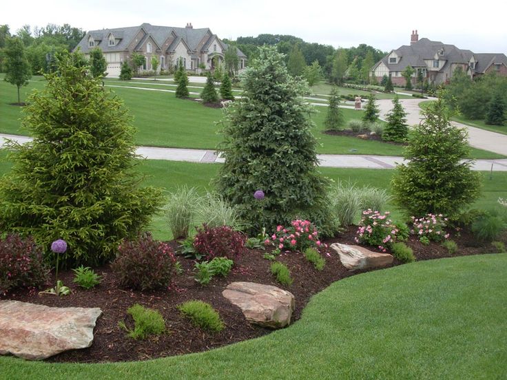 a lush green field filled with lots of trees and flowers next to a stone wall