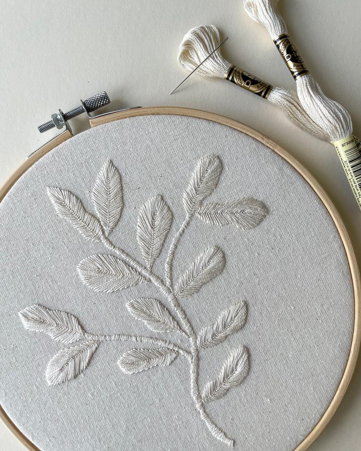 a close up of a embroidery on a table with yarn and scissors next to it