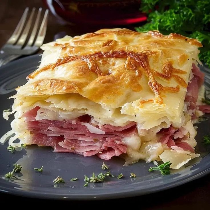 a piece of ham and cheese pie on a plate with a fork next to it