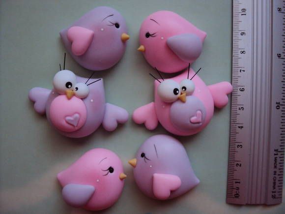 pink and purple birds are sitting next to a measuring ruler on a table with one bird in the middle