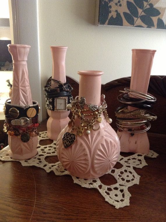 three pink vases sitting on top of a wooden table next to a lace doily