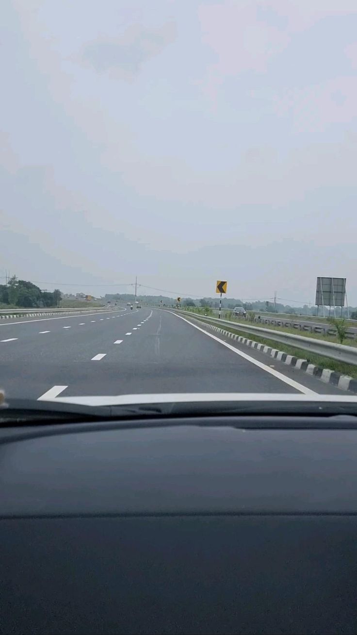 a car driving down an empty highway on a cloudy day