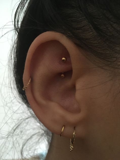 a woman's ear with two small gold hoops