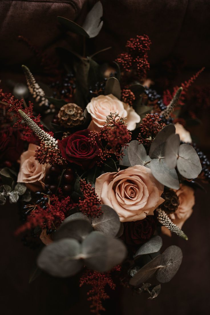 a bouquet of flowers with leaves and berries