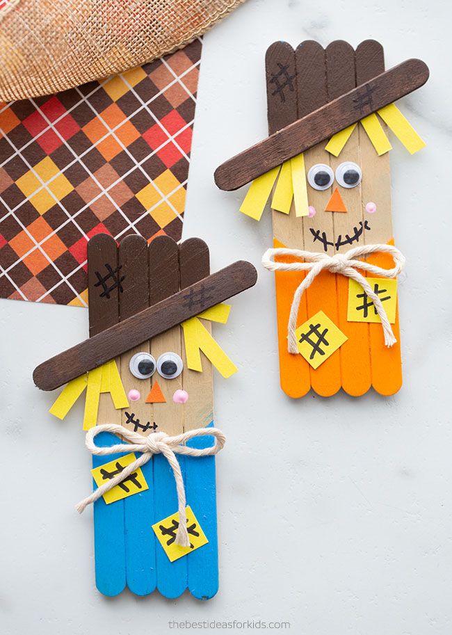 two scarecrows made out of popsicle sticks are sitting on a white surface