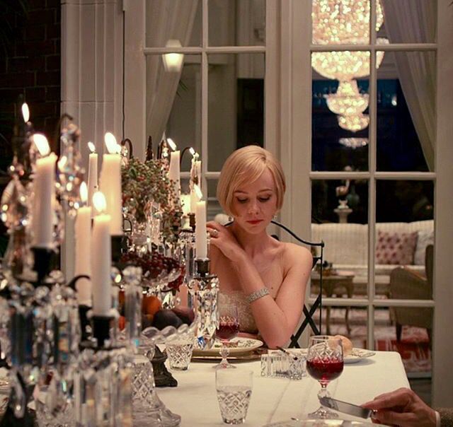 a woman sitting at a table in front of a chandelier filled with candles