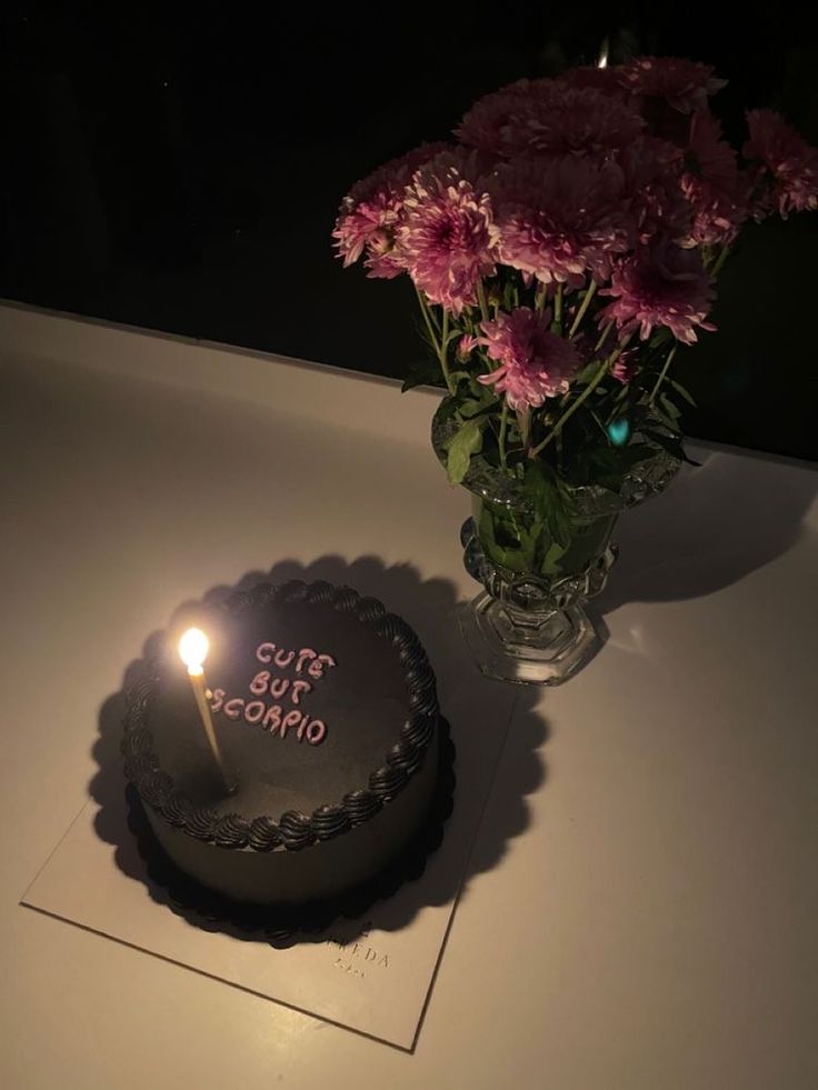 a birthday cake sitting on top of a table next to a vase with flowers