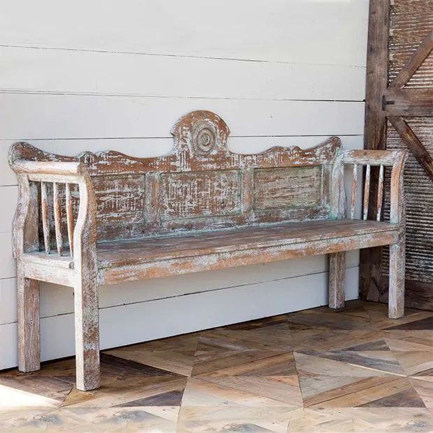 an old wooden bench sitting in front of a white wall