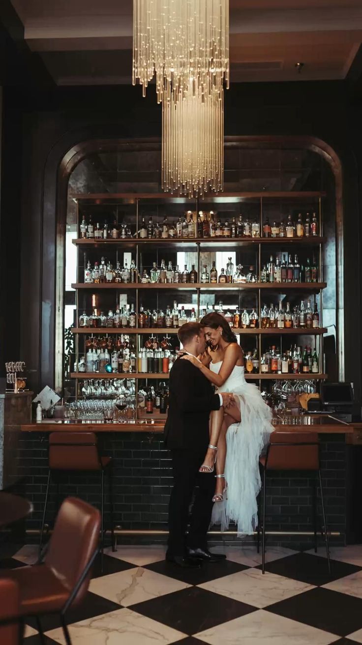 a man and woman standing in front of a bar with liquor bottles on the shelves