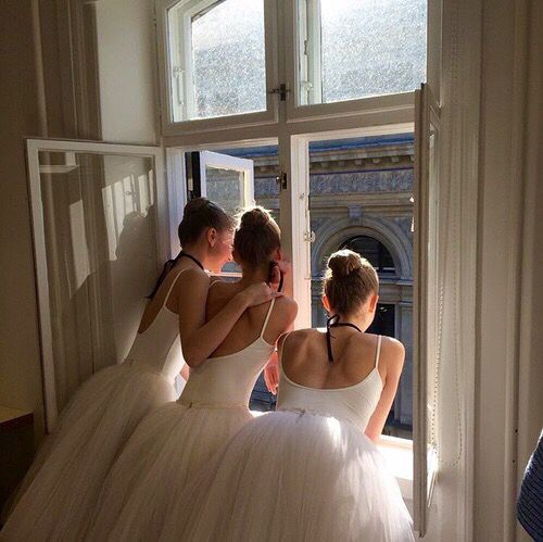 three women in white dresses are looking at each other through the window while wearing tulle skirts