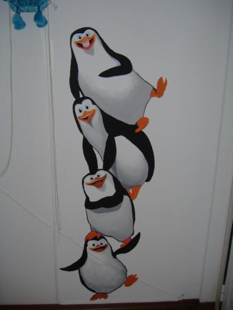 a group of penguins standing on top of each other in front of a white wall