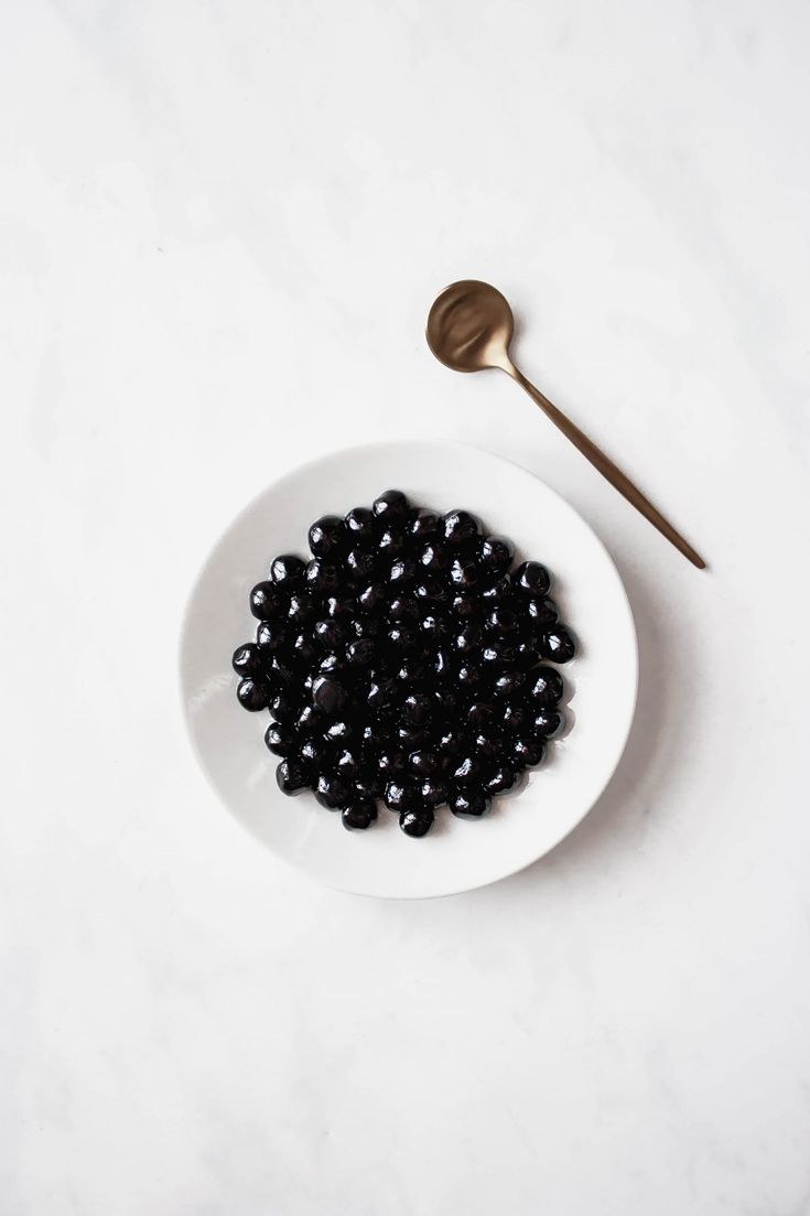 a white plate topped with black beans next to a spoon