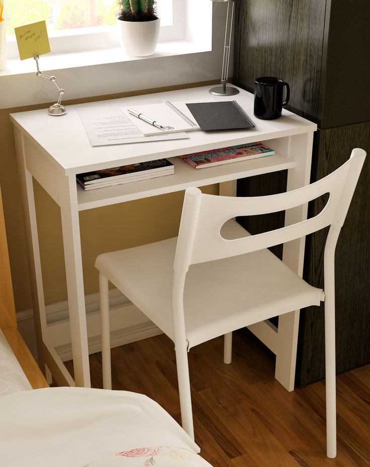 a white desk with a laptop computer on top of it next to a chair and window