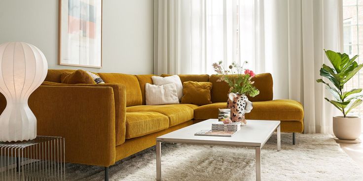 a living room with yellow couches and white rugs on the floor in front of large windows