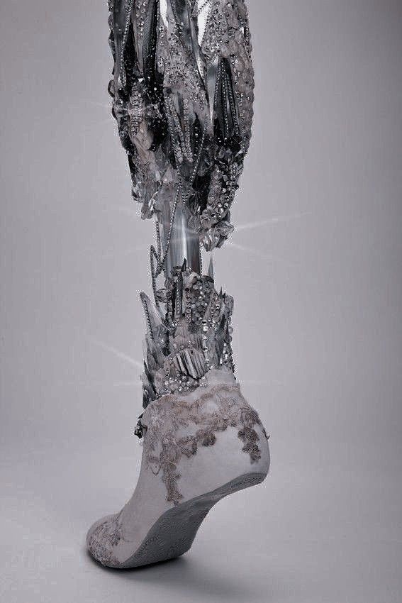 an artistic sculpture made out of silver and black objects on a gray background with the foot in the air