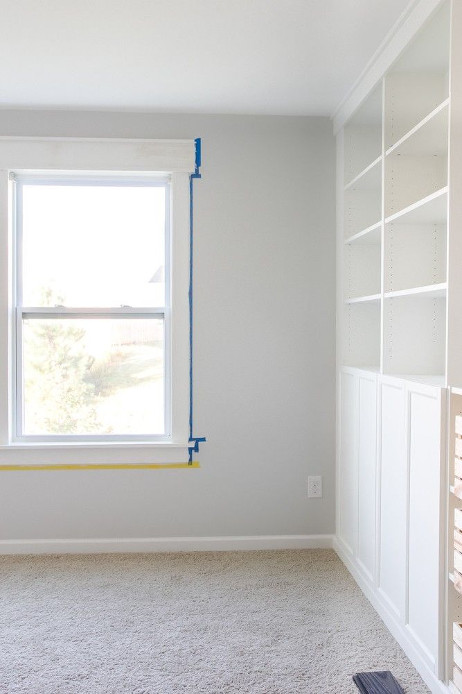 an empty room with white walls and blue tape on the window sill in front of it