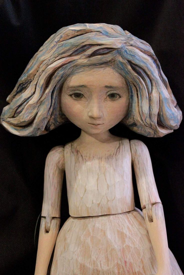 a wooden doll is wearing a white dress and a large hat on top of it's head