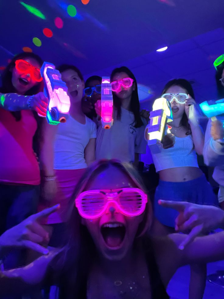 a group of young women wearing neon glasses and holding up cell phones in front of their faces