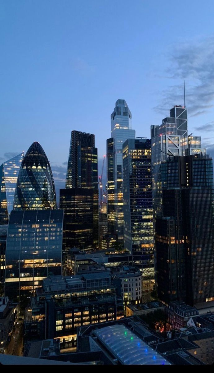 the city skyline is lit up at night with skyscrapers in the foreground and other tall buildings